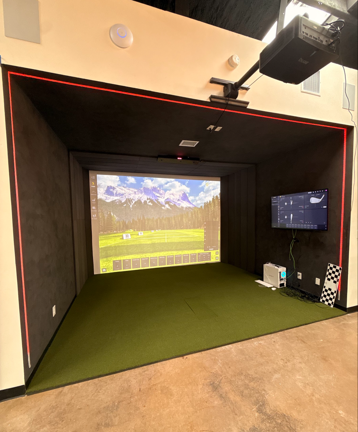 Built in golf simulator bay with a ceiling mounted projector and wall TV
