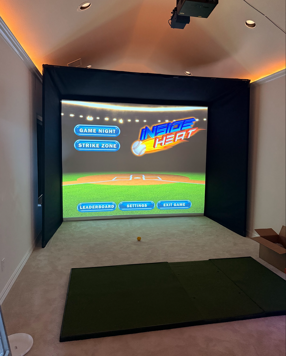 Golf simulator enclosure in a home room with a hitting mat