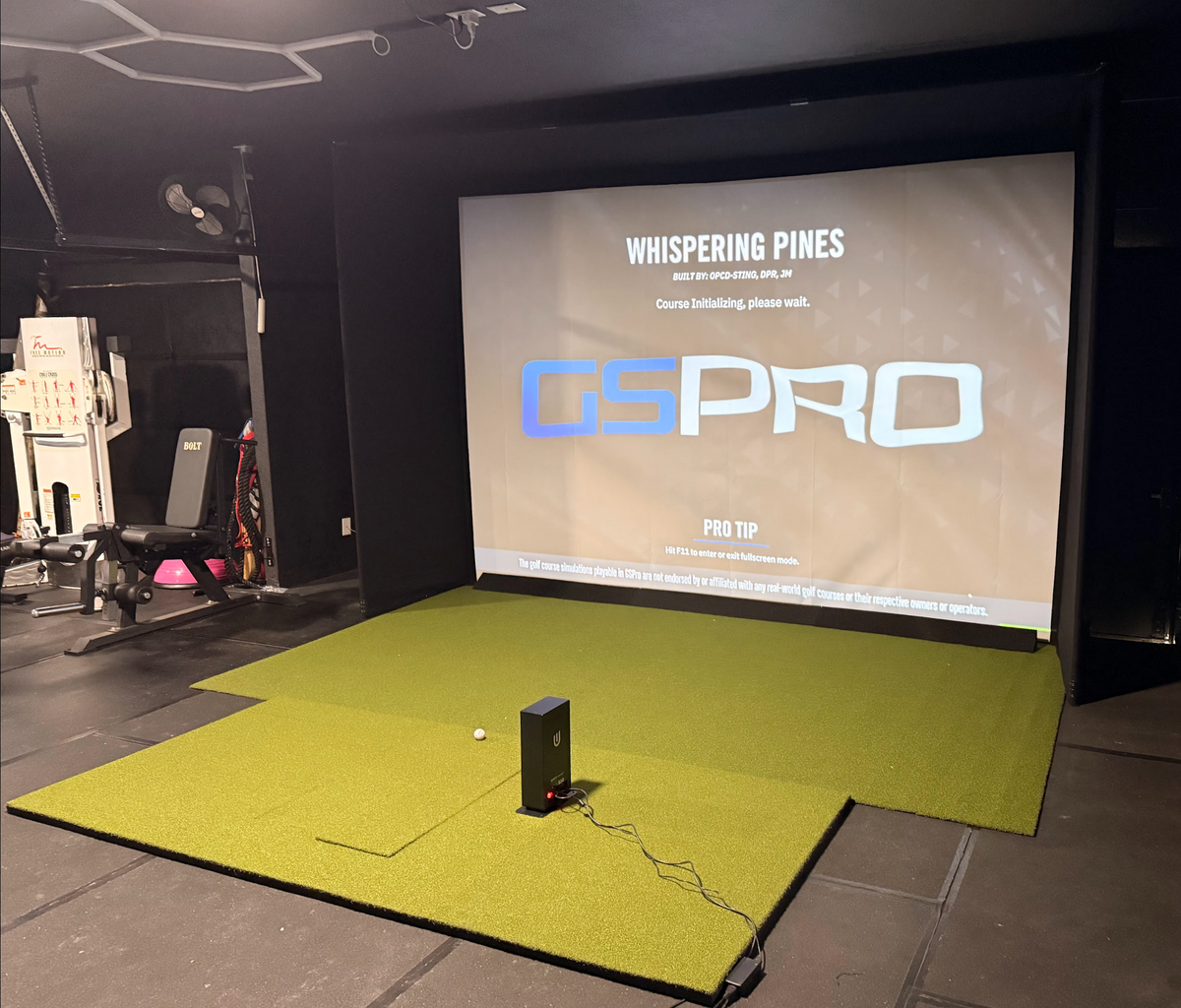 Golf simulator enclosure running GSPro on a green turf platform